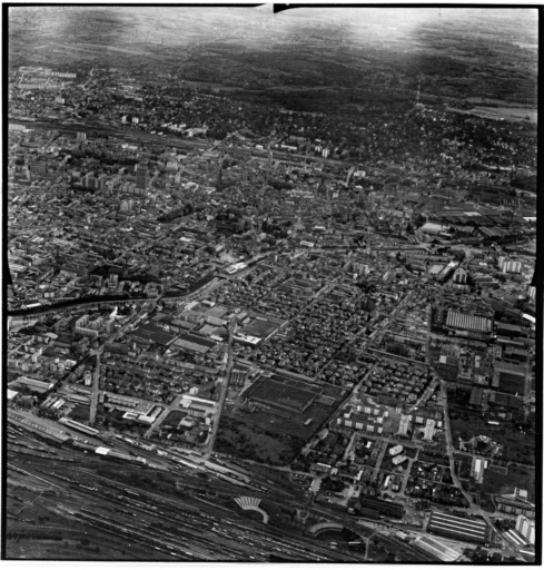 Vue aérienne : la ville vue du nord. A droite au premier plan : la gare du nord, la filature peignée Gluck et la Cité.