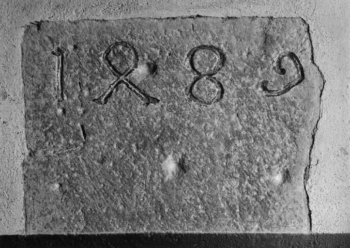 Bas-côté sud, mur est (extrémité sud), face interne du contrefort (visible dans la sacristie), pierre avec inscription. Etat en 1974, avant restauration.