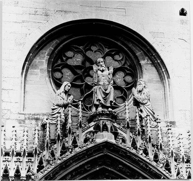 Façade ouest, sommet du portail : statue du Christ entre la Vierge et Saint Jean Baptiste.