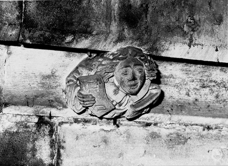 Façade sud, relief sur la corniche du bas côté, caché par la chapelle de la Vierge : jeune homme tenant un phylactère (S4).