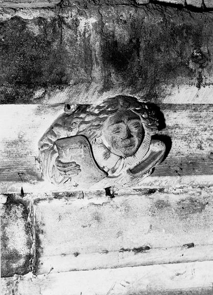 Façade sud, relief sur la corniche du bas côté, caché par la chapelle de la Vierge : jeune homme tenant un phylactère (S4).