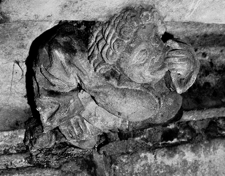 Façade sud, relief sur la corniche du bas côté, caché par la chapelle de la Vierge : homme grimaçant portant une main à la bouche (S5)