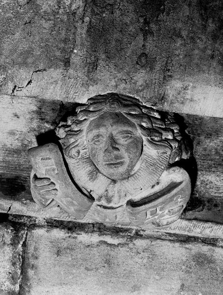 Façade sud, relief sur la corniche du bas côté, caché par la chapelle de la Vierge : jeune homme tenant un phylactère (S4).