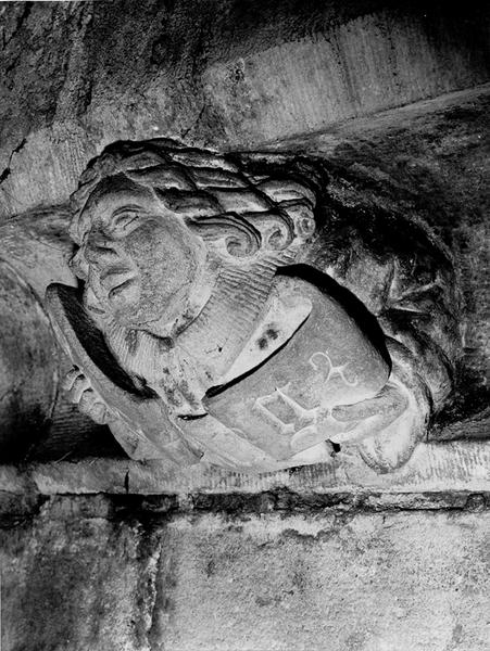 Façade sud, relief sur la corniche du bas côté, caché par la chapelle de la Vierge : jeune homme tenant un phylactère (S4).