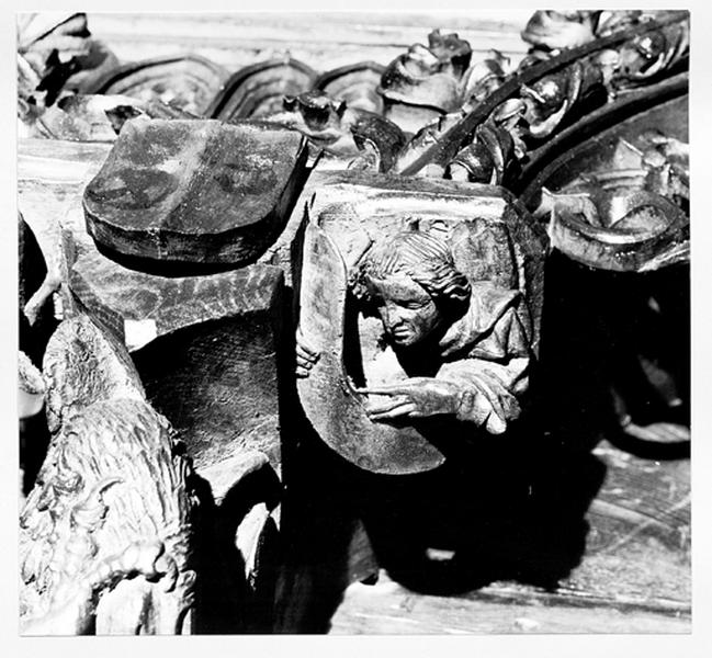 Mur sud du choeur, stalles hautes, 2ème groupe, console 3, relief à droite de la console : homme portant une banderole.