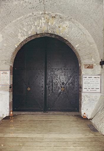 Sous le portique : la porte blindée.