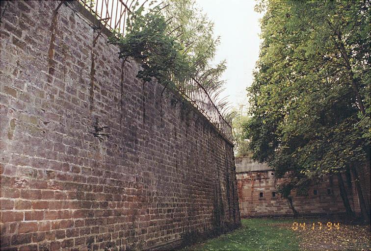 Le fossé de flanquement Ouest : mur de contrescarpe et les grilles. Au fond la caponnière d'épaule.