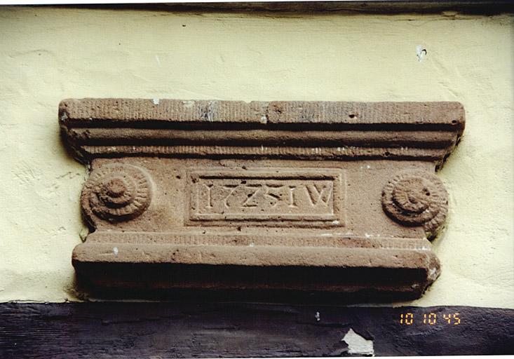Corps de bâtiment ouest. Remploi, d'un socle de poêle (?), au-dessus d'une porte dans l'élévation sur cour.