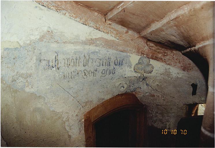 Corps de bâtiment ouest avec tourelle d'escalier dans-oeuvre, de 1577. Détail d'une porte intérieure vers la maison nord et décor peint avec inscription pieuse.