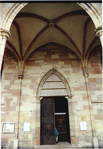 Vue de la travée centrale du porche, avec porte principale de l'église, depuis le sud.