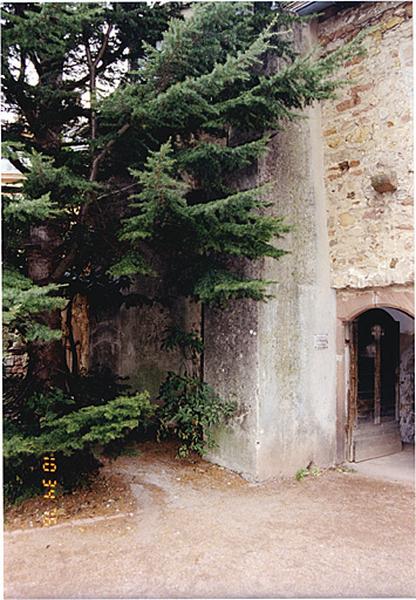 Vue partielle du mur ouest du bâtiment abritant la chapelle étayée par des contreforts modernes.