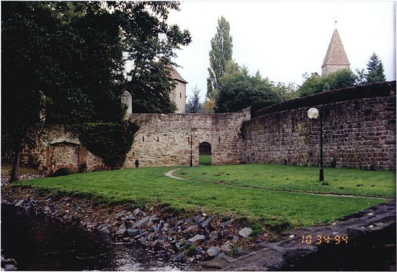 Courtine ouest de la ville (à droite) et courtine sud du Bruch. Vue extra-muros depuis le sud. Au fond, la tour Schartenturm de l'abbaye et la tour romane occidentale de l'église Saint-Pierre-Saint-Paul.