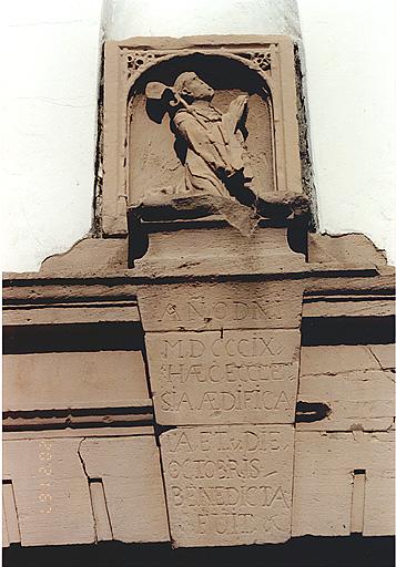 Elévation antérieure. Relief d'un moine agenouillé portant une crosse, placé dans le fronton du portail (remploi).