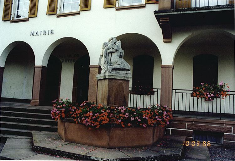Vue de la fontaine avec monument aux morts des deux guerres (J), rue de Mattstall.