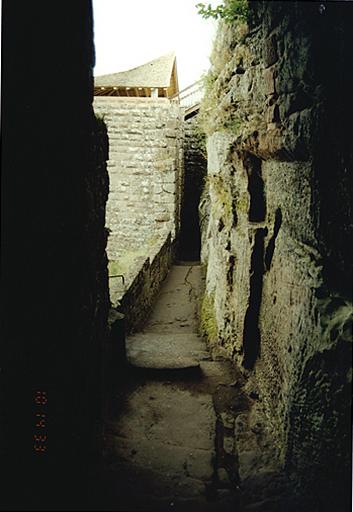 Vue d'ouest en est de la rampe d'accès le long du rocher, côté nord, entre la tour demi-circulaire et la tour d'escalier.