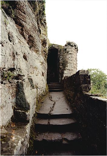 Vue d'est en ouest de la rampe d'accès le long du rocher, côté nord, entre la tour d'escalier et la tour demi-circulaire.