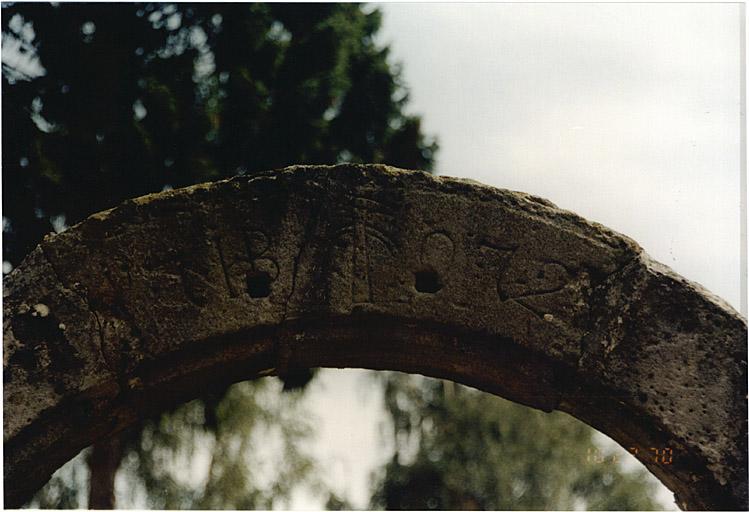 Porte (A) de jardin, située rue de l'Eglise. Détail avec emblème de maréchal-ferrant et date 1772.