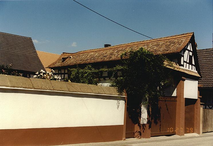 Vue de la dépendance à pignon sur rue et des portes piétonne et charretière.
