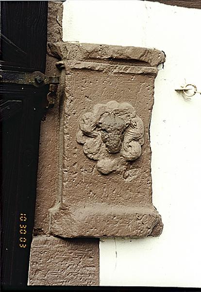 Grange en fond de cour. Vue de l'élément sculpté en remploi.