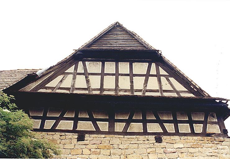 Mur-pignon de la grange : motifs peints et piquetés sur le crépi.