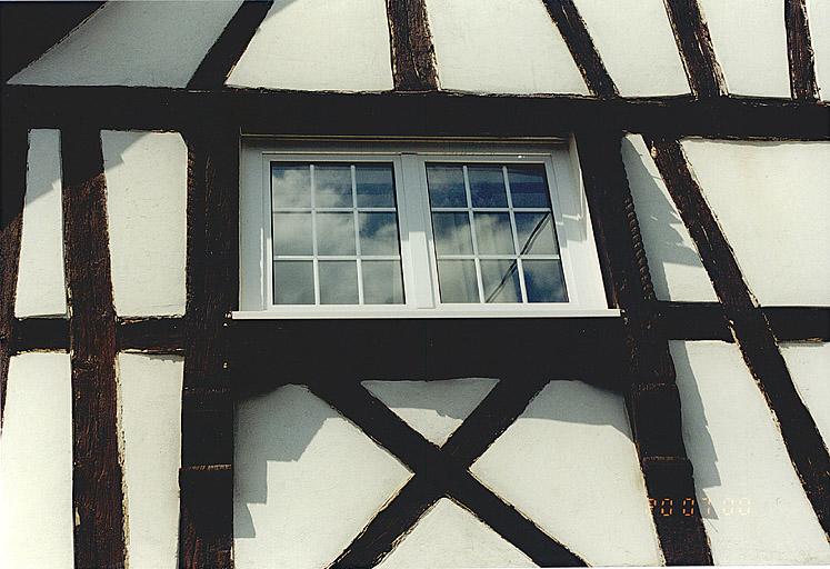 Mur-pignon du logis, fenêtre à chambranle sculpté.