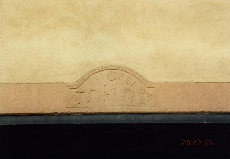 Ferme, 90 rue de l'Eglise : emblème de maréchal-ferrant sur le linteau d'une dépendance, daté 1856.