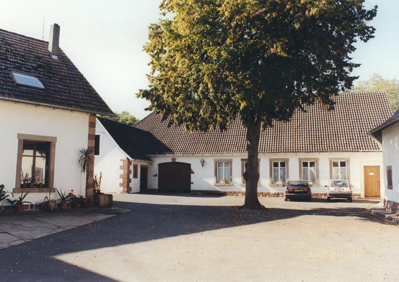 Vue des bâtiments autour de la cour : à gauche le moulin, au fond, la grange (atelier).