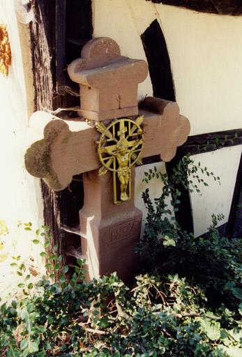 Croix de chemin (C), contre l'abri de garde-champêtre, datée 1827.
