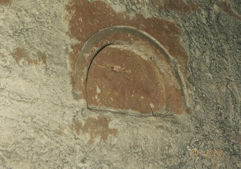 Mur intérieur de la tour-porche, pierre sculptée d'un arceau, remployée au niveau des cadrans d'horloge.