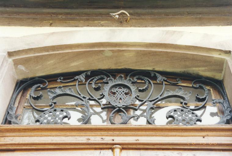 Avant-corps ouest, porte surmontée d'une fenêtre en dessus-de-porte, fermée par une grille du 18e siècle.