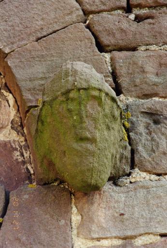 Tour, face nord, porte, tête sculptée à droite du tympan.