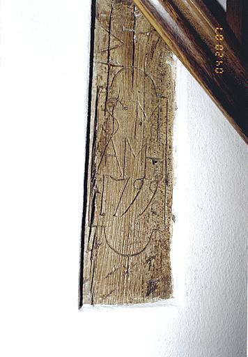 Vue du fragment de poteau cornier millésimé en réemploi dans l'escalier du logis.