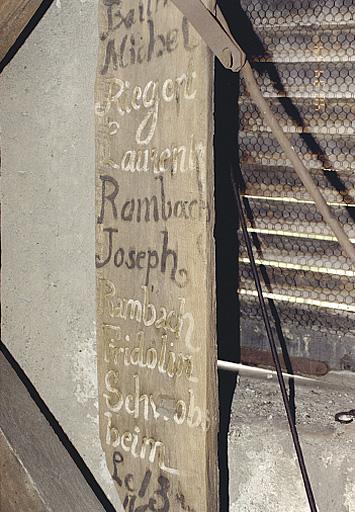 Vue des inscriptions sur une planche dans la chambre des cloches de la tour-porche.