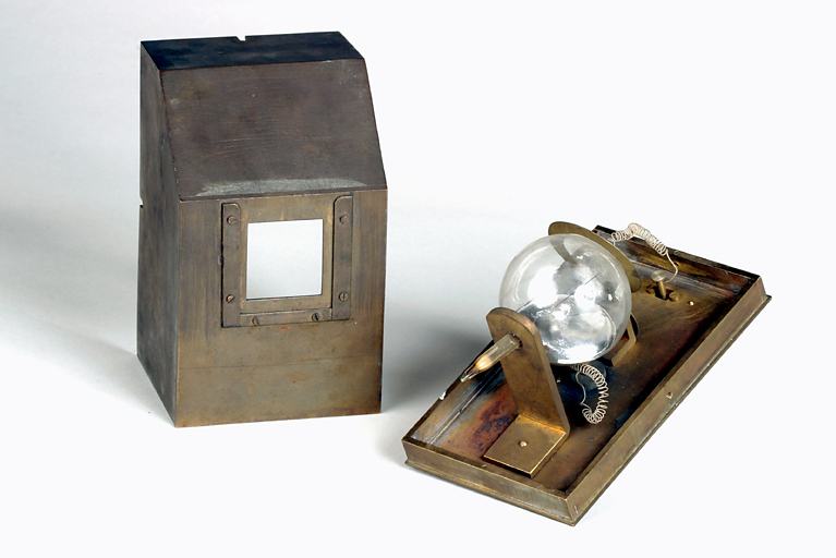 Vue d'ensemble de trois-quart de la lampe (à droite) et du boîtier de protection debout (à gauche).