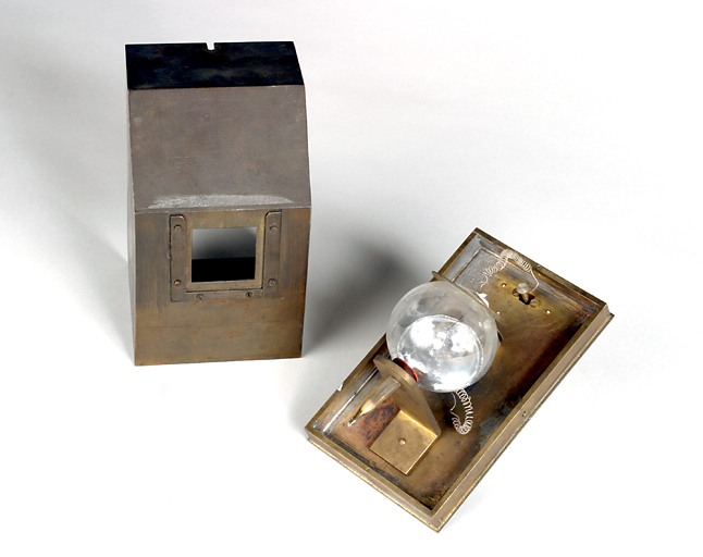 Vue d'ensemble de trois-quart de la lampe (à droite) et du boîtier de protection debout (à gauche).