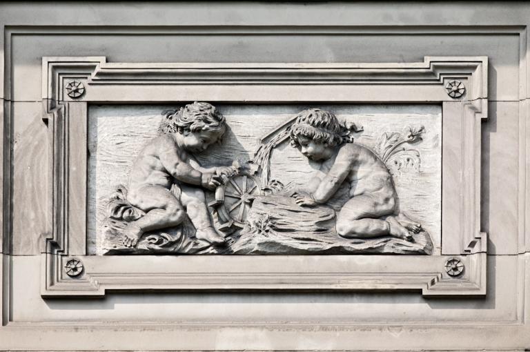 Vue du décor ornant le côté gauche du fronton de l'aile ouest, sur la façade sud : allégorie de la maîtrise des éléments de la nature par la physique - l'eau (avec la roue à eau).