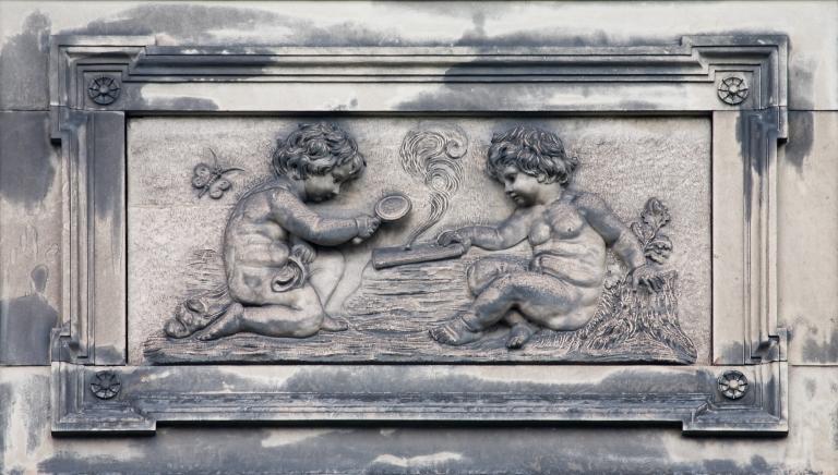 Vue du décor ornant le côté droit du fronton de l'aile est, sur la façade sud : allégorie de la maîtrise des éléments de la nature par la physique - le feu (avec la loupe).