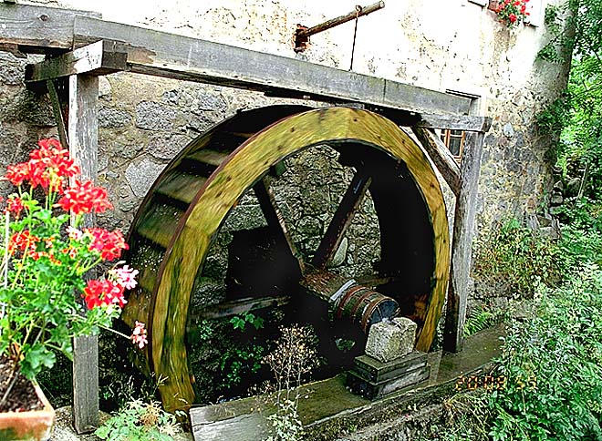 La roue à augets contre le mur-pignon.