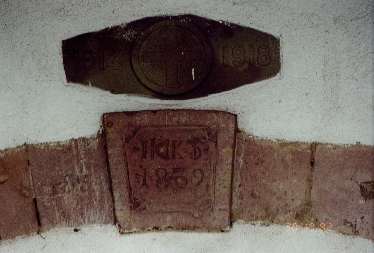 Vue de détail. Clé de l'arc en plein cintre ouvrant sur l'étable et remploi d'un bas-relief de la Croix Rouge.