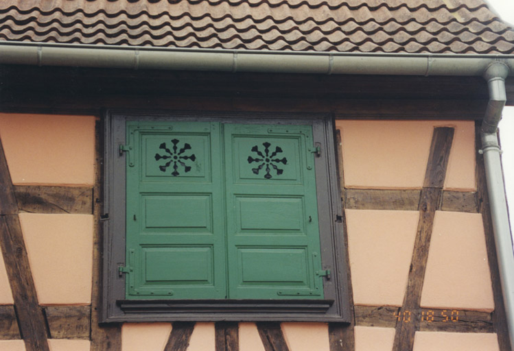 Détail d'une fenêtre aux volets ajourés.
