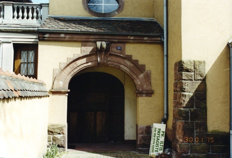 Entrée secondaire. Sur le contrefort d'angle, pierre commémorative de la construction, 1926.