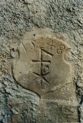 Pierre avec emblème familial et date de 1548, remployée dans le gouttereau de l'écurie. Vue de détail.