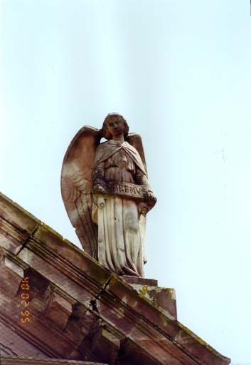 Vue de détail : statue d'un ange portant l'inscription ' adoremus ' gravée sur un phylactère.