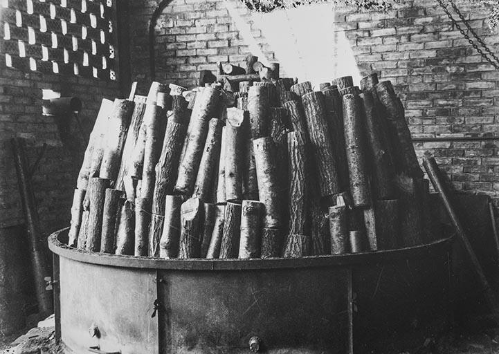 Fabrication de charbon de bois (ou de gaz carbonique ?) : 3e étape du chargement du bois dans la machine.