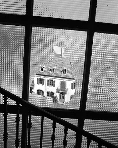 Façade sur cour des bureaux (extrémité occidentale), vue au travers d'une vitre brisée.