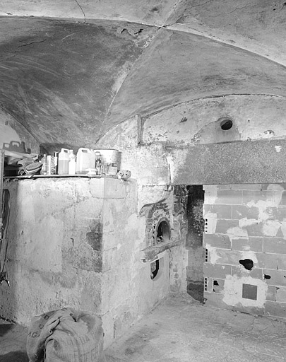 Ancienne cuisine voûtée avec cheminée et four au rez-de-chaussée.