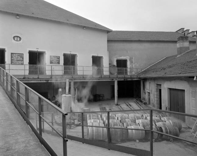 Façades sur cour des chais. Au centre de la cour : fûts de vieillissement du vin jaune.