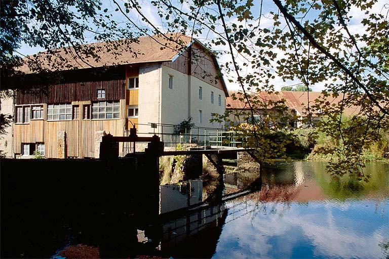 Le moulin Choudet vu de trois quarts arrière. Au premier plan, bassin de retenue.