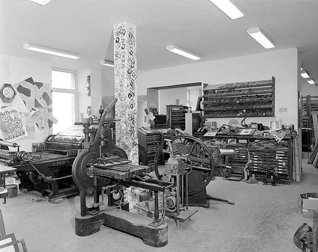 Salle d'impression et mise en forme : presses à platine Stanhope, Minerve et Dubuit, presse à cylindre Voirin, agrafeuses à plat et à cheval, rangs à pupitre et étagères.