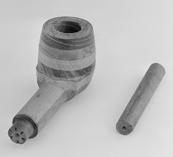 Détail d'un tuyau de bois et d'un second, inséré dans la tige d'une pipe en contreplaqué.